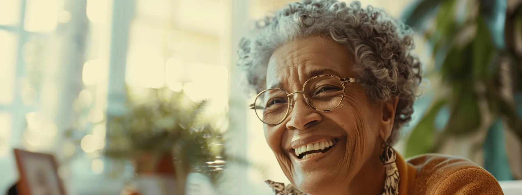 a senior woman smiling while comfortably reviewing final expense insurance policy options with a caring insurance agent.